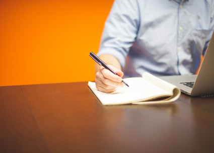 Hand hält Stift über Notizheft